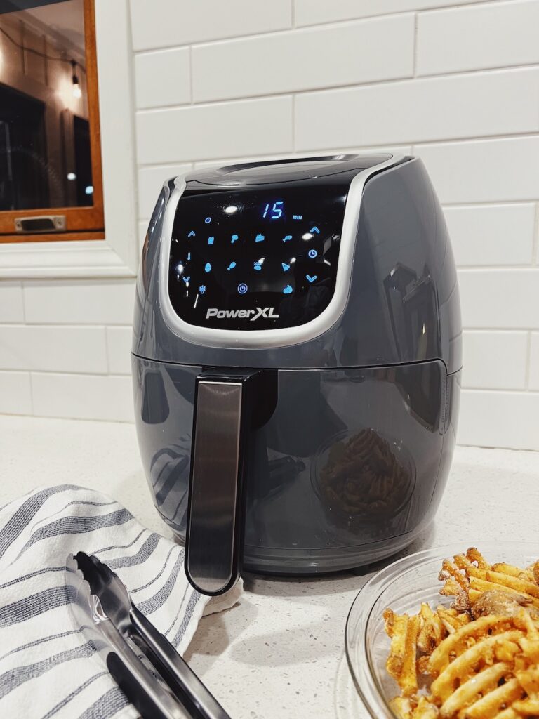 grey air fryer with french fries and tongs