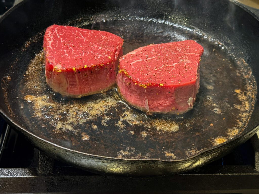 filet mignon searing in a cast iron skillet